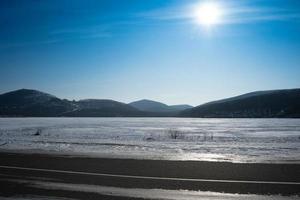 zeegezicht met felle zon en sneeuw bedekte kust foto