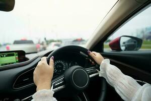 vrouw het rijden auto. meisje gevoel gelukkig naar rit Holding stuurinrichting wiel en op zoek Aan weg foto