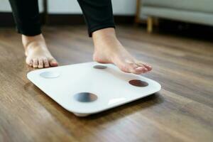 verliezen gewicht. dik eetpatroon en schaal voeten staand Aan elektronisch balans voor gewicht controle. meting instrument in kilogram voor eetpatroon. foto