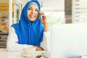 moslim vrouw kantoor arbeider. vrouw pratend Aan telefoon in kantoor foto