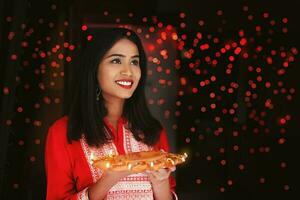 mooi Indisch vrouw Holding diya thali voor diwali viering foto