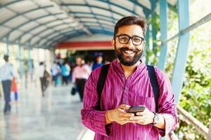 gebaard Indisch Mens Aan metro station gebruik makend van app in zijn smartphone foto