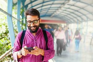 gebaard Indisch Mens Aan metro station gebruik makend van app in zijn smartphone foto