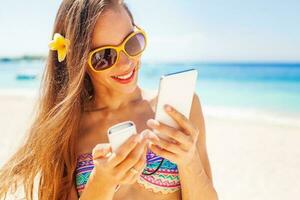 vrouw toerist gebruik makend van portable macht bank naar in rekening brengen haar telefoon Aan een strand foto