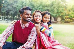 mooi Indisch familie knuffelen elk andere gedurende de picknick in de park foto
