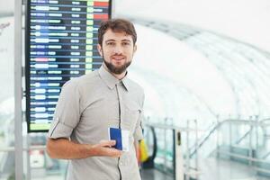 Mens in luchthaven Holding zijn paspoort en haast voor zijn vlucht in de buurt de schema foto