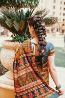 terug kant portret van Indisch vrouw vervelend Saree en mooi gevlochten kapsel Aan haar lang haar- foto