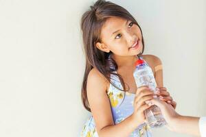 helpende hand die een fles water geeft aan arme kind foto