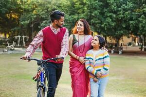 mooi Indisch familie met weinig 10 jaar oud dochter wandelen met fiets buitenshuis in een park foto
