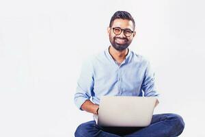 knap Indisch Mens zittend en werken Aan laptop over- studio wit achtergrond foto