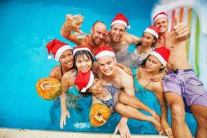 gemengd geracet groep van negen mensen vieren Kerstmis in een zwemmen zwembad foto