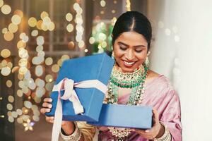 prachtig Indisch vrouw in traditioneel sieraden opening een geschenk foto