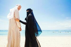 moslim paar Aan een strand vervelend traditioneel jurk foto