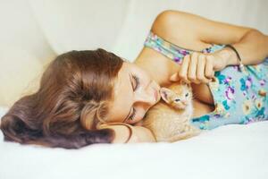 vrouw ontspannende Aan een bed met een heel schattig katje foto