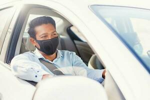 Indisch Mens in beschermend gezicht masker het rijden een auto gedurende coronavirus pandemisch in Indië foto