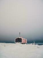 verticaal minimalistisch achtergrond met van eenzaam rood cabine in winter. dubladom Aan de berg volodyanaja kandalaksha, Moermansk regio in Rusland. foto