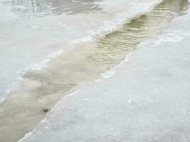 erosie van overstroming wateren. voorjaar stroom. sneeuw gewassen weg door een stroom foto