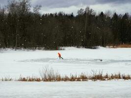 solo opleiding van een hockey speler Aan een geïmproviseerde ijs baan Aan een bevroren meer. gezond levensstijl, sport- concept foto