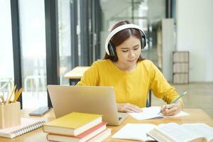 vrouw aan het leren online gebruik makend van laptop en schrijven notities. foto