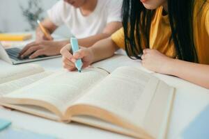 dichtbij omhoog een Aziatisch studenten zijn lezing boeken en studie, bijles samen. foto