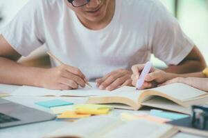 dichtbij omhoog een Aziatisch studenten zijn lezing boeken en studie, bijles samen. foto