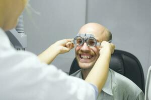 Mens onderzoeken gezichtsvermogen in optisch kliniek. foto