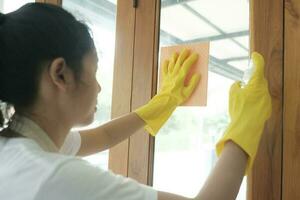 jong Aziatisch vrouw schoonmaak venster. foto