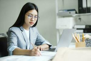 jong Aziatisch zakenvrouw werken Bij kantoor gebruik makend van laptop. foto