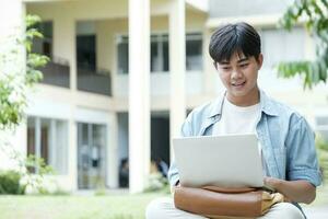 jong collage leerling gebruik makend van computer en mobiel apparaat aan het studeren online. foto