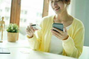 Aziatisch vrouw handen Holding credit kaart en gebruik makend van cel, slim telefoon. foto