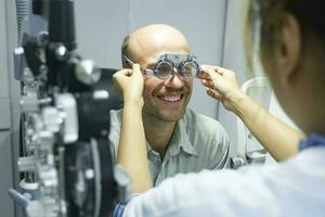Mens onderzoeken gezichtsvermogen in optisch kliniek. foto
