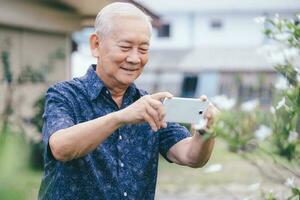 gelukkig Aziatisch senior Mens nemen een afbeelding met mobiel telefoon. foto