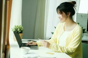 Aziatisch vrouw gebruik makend van laptop en credit kaart voor online winkelen. foto