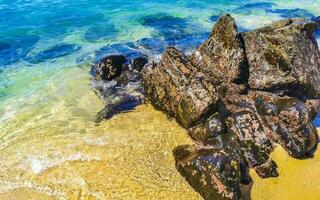 strand zand blauw turkoois water golven rotsen panorama puerto escondido. foto