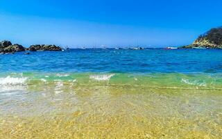 strand zand blauw turkoois water golven rotsen panorama puerto escondido. foto