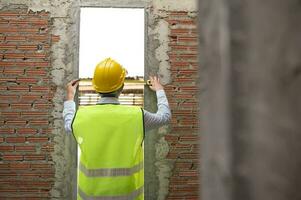 een Aziatisch bouwkunde Mens vervelend veiligheid helm controle bouw plaats analyseren over project vooruitgang foto