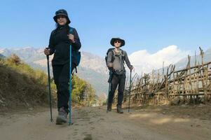 een jong paar reizigers trekking in poon heuvel visie punt in ghorepani, Nepal foto