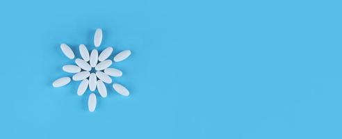 bloemvorm gemaakt van witte tabletten op blauwe achtergrond met kopie ruimte