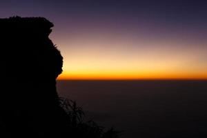 zonsopgang en zee van mist bij phu chi fa in het vroege ochtendsilhouet en toeristen op het puntje van de heuvel