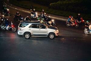 ho chi minh stad, Vietnam - apr 14, 2023 verkeer jam Bij dien bien phu rotonde met haar vier gezichten klok toren een symbool van ho chi minh stad. licht spoor van auto's. foto