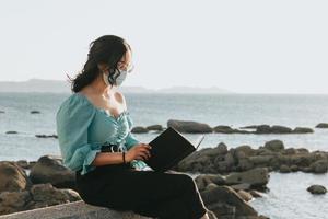 jonge vrouw lezen op het strand tijdens een super zonsondergang tijdens het gebruik van een masker ontspannen en inspirerende concepten met kleurrijke kopie ruimte levensstijl