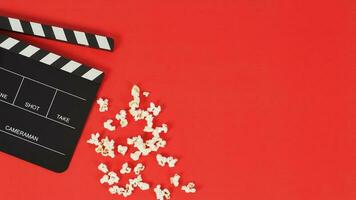 zwart klepel bord of film leisteen en popcorn Aan een rood achtergrond. nieuw foto