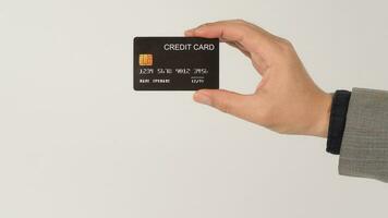 een hand- is Holding zwart credit kaarten en vervelend pak Aan wit achtergrond. foto