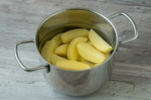 rauw geschild aardappelen in een pot van water voordat Koken foto