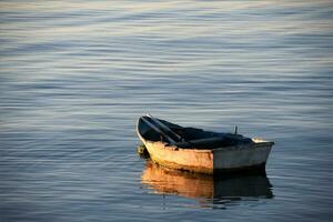 klein boot in de zee Bij zonsondergang foto