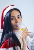 De aziatische vrouw die de hoed van de Kerstman draagt viert Kerstmis door gelukkig champagne te drinken