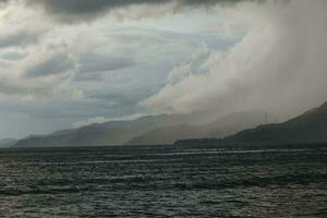 storm over- de zee met bergen in de achtergrond foto