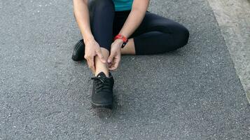 vrouw gewond van rennen park en zittend Aan de verdieping hand- Holding de enkel voelde een veel pijn, gezondheid zorg sport concept foto