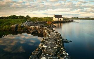 mooi oever van het meer landschap met vissers hut weerspiegeld in meer Bij puinhoop in Connemara nationaal park, provincie Galway, Ierland foto
