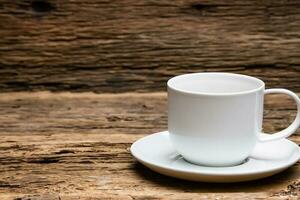een wit kop van koffie zit Aan een houten tafel. foto